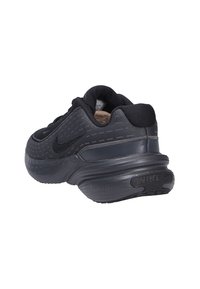 Zapatilla deportiva negra con parte superior de malla texturizada, collar acolchado y media suela de Phylon. Cuenta con una suela de goma con forma curvada y marca Nike.