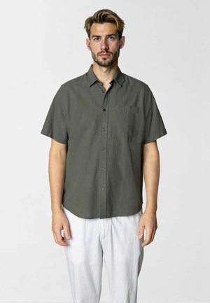 Kurzärmliges, knöpfbares Hemd aus dunkelolivgrünem Stoff, mit einer aufgesetzten Tasche auf der linken Brust und einer glatten Textur.