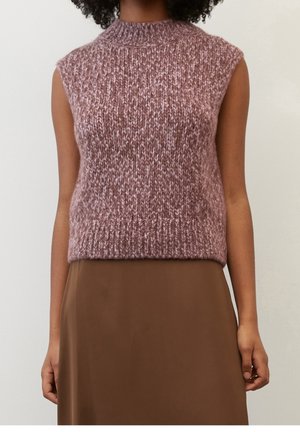 Ærmeløs strikket bluse i mauve med ribkant, båret over en brun nederdel på en stående person mod en ensfarvet baggrund.