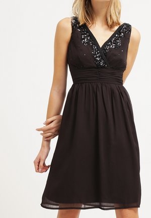 Ärmelloses schwarzes knielanges Kleid mit V-Ausschnitt, verziert mit schwarzen Pailletten auf der Brust und geraffter Taillendetail.