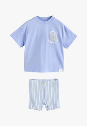 Lichtpaarse T-shirt met korte mouwen, voorzien van een zonafbeelding en de tekst "Sunrise to Sunset", gecombineerd met geribbelde korte broek met blauwe, witte en gele strepen.