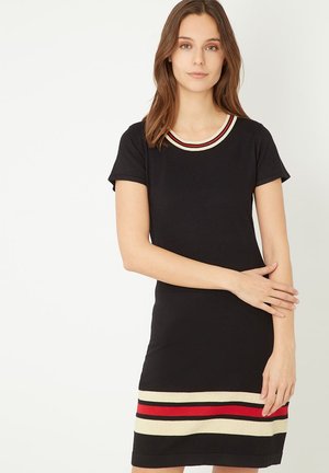 Vestido de punto negro con mangas cortas, que cuenta con un cuello acanalado en rojo y beige, y un dobladillo a rayas en rojo, beige y negro.