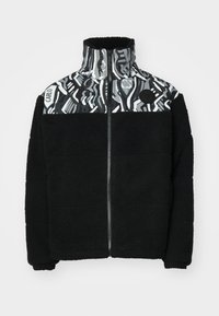 Black fleece jacket with a high collar, featuring a geometric gray and white patterned panel on top and a circular logo detail.