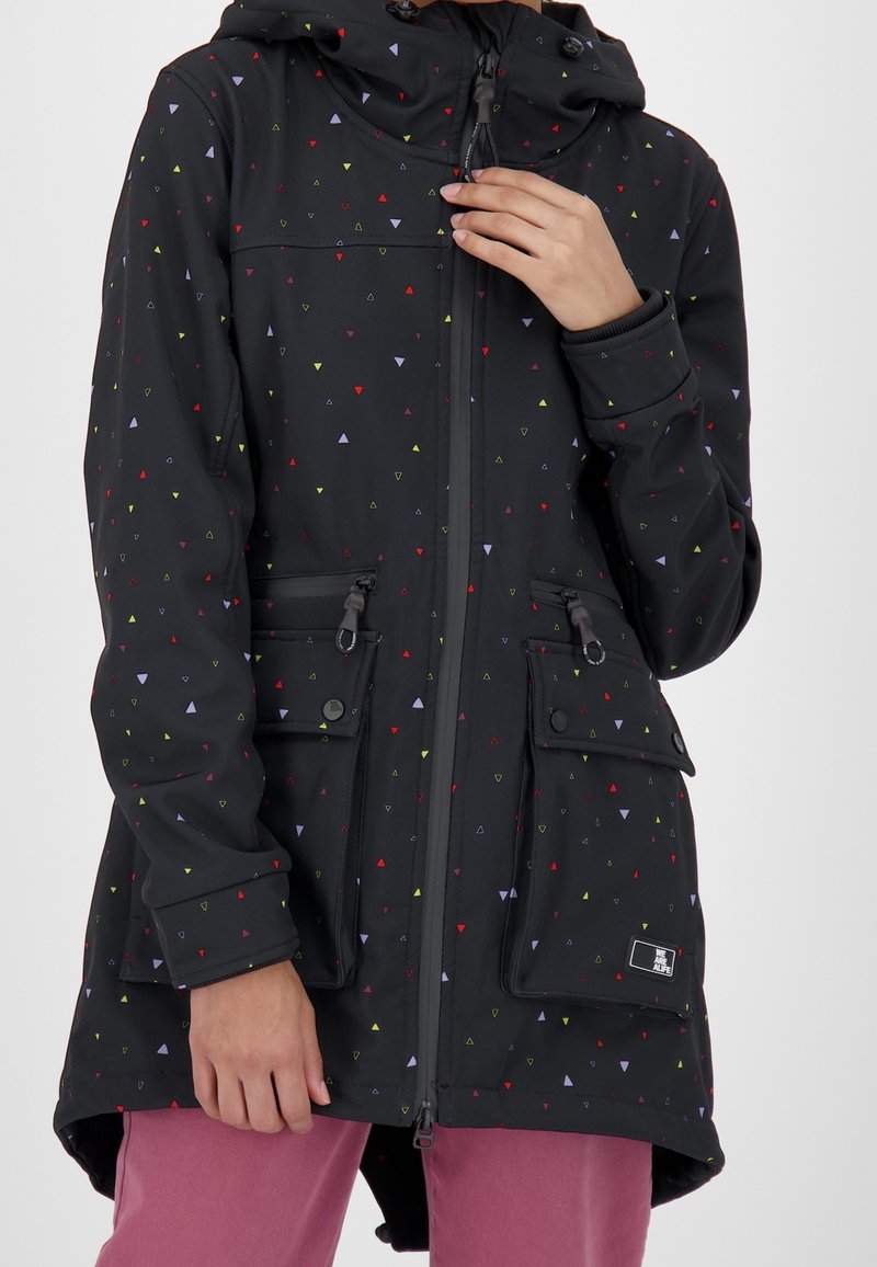 Veste noire à capuche avec de petits motifs triangulaires colorés, fermeture éclair frontale et grandes poches avant, portée sur un pantalon rose.