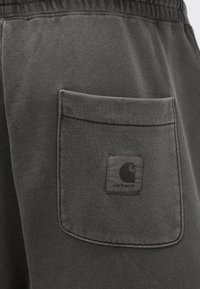 Γκρι φόρμα με υφασμάτινη υφή, με πίσω τσέπη και ορθογώνιο μαύρο λογότυπο Carhartt. Σχέδιο με ελαστική μέση.