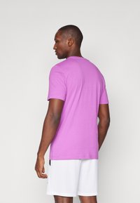 Kortærmet T-shirt i en livlig pink farve, med en rund halsudskæring og en glat tekstur, vist fra ryggen med hvide shorts.