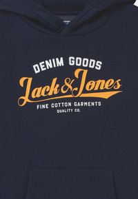 Námořnická bavlněná mikina s kapucí s předním potiskem, který zní "DENIM GOODS Jack & Jones" v bílé a oranžové barvě; zahrnuje přední kapsu.