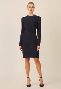 Strickkleid in Dunkelblau mit einem Rautenmuster, Rundhalsausschnitt und langen Ärmeln. Der Saum endet über dem Knie.