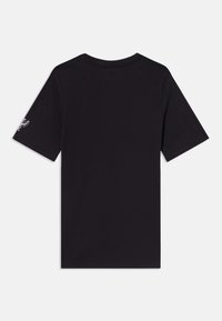 T-shirt noir à manches courtes en coton, avec un col rond, un design simple et un petit graphisme sur la manche gauche.