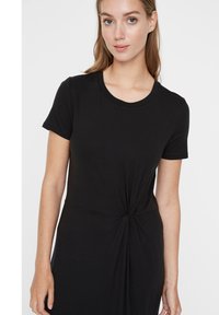 Μαύρο φόρεμα μπλούζα από μαλακό ύφασμα, με στρογγυλή λαιμόκοψη και λεπτομέρεια από στριμμένο κόμπο στη μέση. Βραχίονες κοντοί, άνετη εφαρμογή.