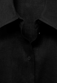 Black linen shirt featuring a classic collar, button closure, and a smooth texture with subtle stitching details.
