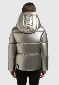 Metaliczna srebrna kurtka puchowa z dużym kapturem, haftowanymi detalami i logo na plecach. Posiada teksturowane, błyszczące wykończenie.