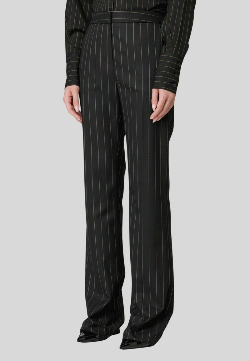 Pantaloni neri a righe con vita alta e gamba ampia; presentano righe verticali verdi e gialle, vestibilità sartoriale e tessuto morbido.