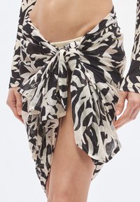 Čiernobiela vzorovaná zavinovacia sukňa z ľahkej látky, ktorá má uzlový dizajn v páse a bočný rozparok.