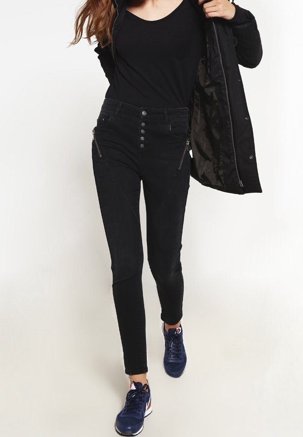 Svarta denim skinny jeans med hög midja, med dragkedjefickor och en rad knappar. Tillsammans med en svart topp och blå sneakers.