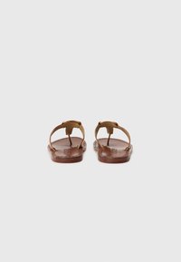 Brune lærsandaler med flad sål, åben bag, og guldfarvede spænde detaljer. Enkelt design med tynde stropper og glat tekstur.