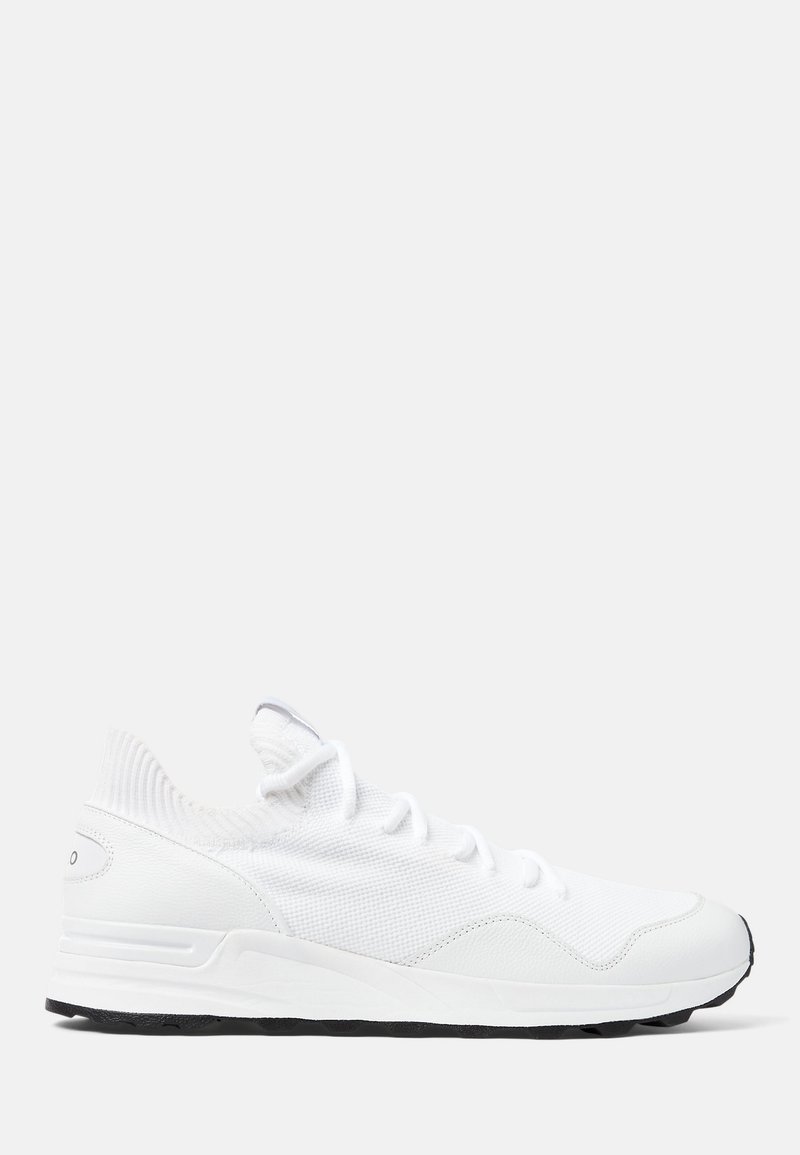 Baskets de sport blanches avec un dessus en tricot, fermeture à lacets, accents texturés et semelle extérieure en caoutchouc noir pour une adhérence optimale.