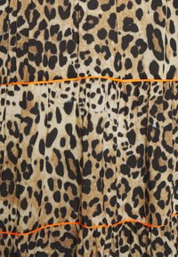 Leopardi-kuvioinen kangas, jossa on beige, ruskea ja musta laikku. Korostaa oranssia kaitaletta rypytetyissä saumoissa, mikä luo tekstuurillisen ja kerroksellisen ilmeen.