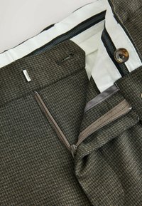 Wool blend trousers featuring a textured houndstooth pattern, side zippered pocket, and button closure with contrasting inner lining.