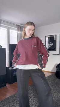 Μπορντό φούτερ με μαύρες και λευκές λεπτομέρειες, χαλαρή εφαρμογή, στρογγυλή λαιμόκοψη; συνδυασμένο με μαύρο παντελόνι σε φαρδύ σχέδιο και λευκό στρώμα από κάτω.