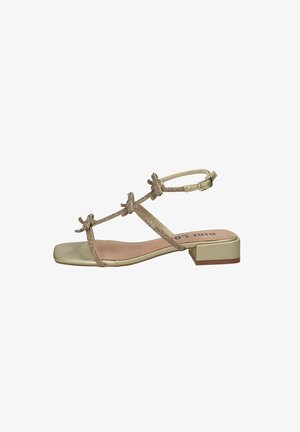 Sandalo piatto beige con punta quadrata, tre sottili cinturini decorati con piccoli fiocchi, cinturino alla caviglia con fibbia e tacco basso a blocco.