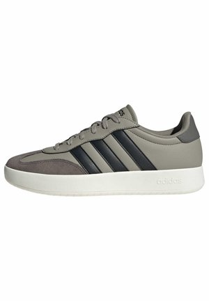 Low-top Adidas sneaker in gray with black stripes, white sole, lace-up design, and suede toe cap, shown from the side on a white background.