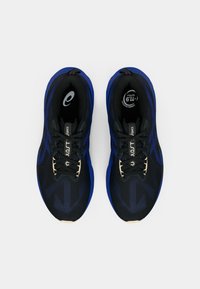 Chaussures de sport noires et bleues avec une tige en mesh respirante, des lacets plats noirs et une semelle en caoutchouc bleu durable. Présente un motif texturé sur la surface.