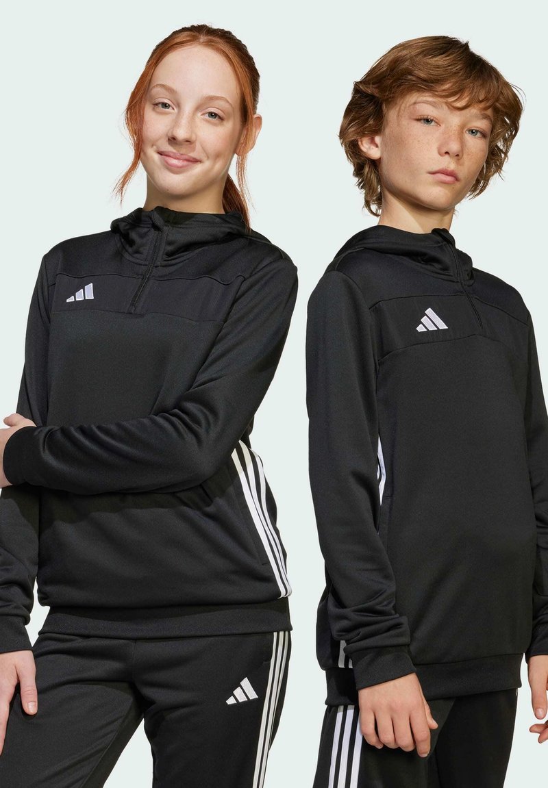 Top e pantaloni sportivi neri con accenti bianchi a tre strisce, caratterizzati da cappuccio con zip e tasche frontali. Realizzati in tessuto liscio.