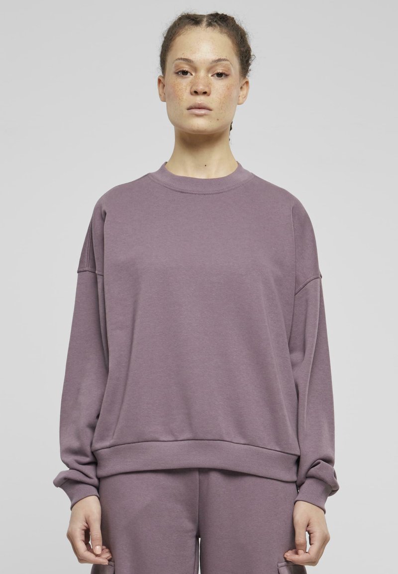 Lila crewneck sweatshirt med sänkta axlar samt ribbad mudd och nederkant. Tillverkad av mjukt material med en slät yta.