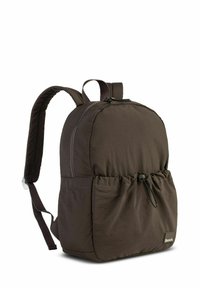 Brown nylon backpack with a rounded shape, adjustable straps, and a front pocket featuring a drawstring closure. Logo displayed on the side.