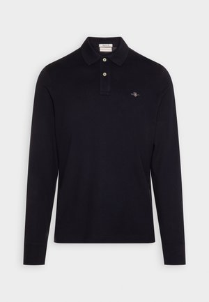 Tricou polo cu mânecă lungă, de culoare albastru închis; are guler cu două butoane, logo brodat pe piept și o textură moale și netedă.