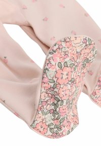 Rosa Strumpfhosen mit floralem Muster auf den Sohlen, die kleine Rosenmotive und grüne Akzente aufweisen, aus einem weichen, dehnbaren Stoff gefertigt.