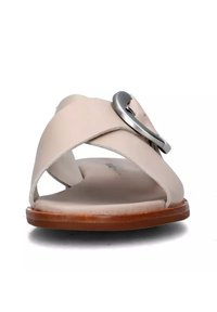 Sandalo in pelle beige con cinghie incrociate, caratterizzato da una fibbia metallica tonda. La suola è marrone e piatta, con una texture liscia.