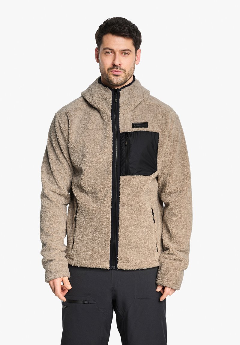 Veste en polaire beige avec une poche poitrine zippée en nylon noir, dotée d'un col montant et de poches latérales, d'une texture douce et d'une coupe décontractée.