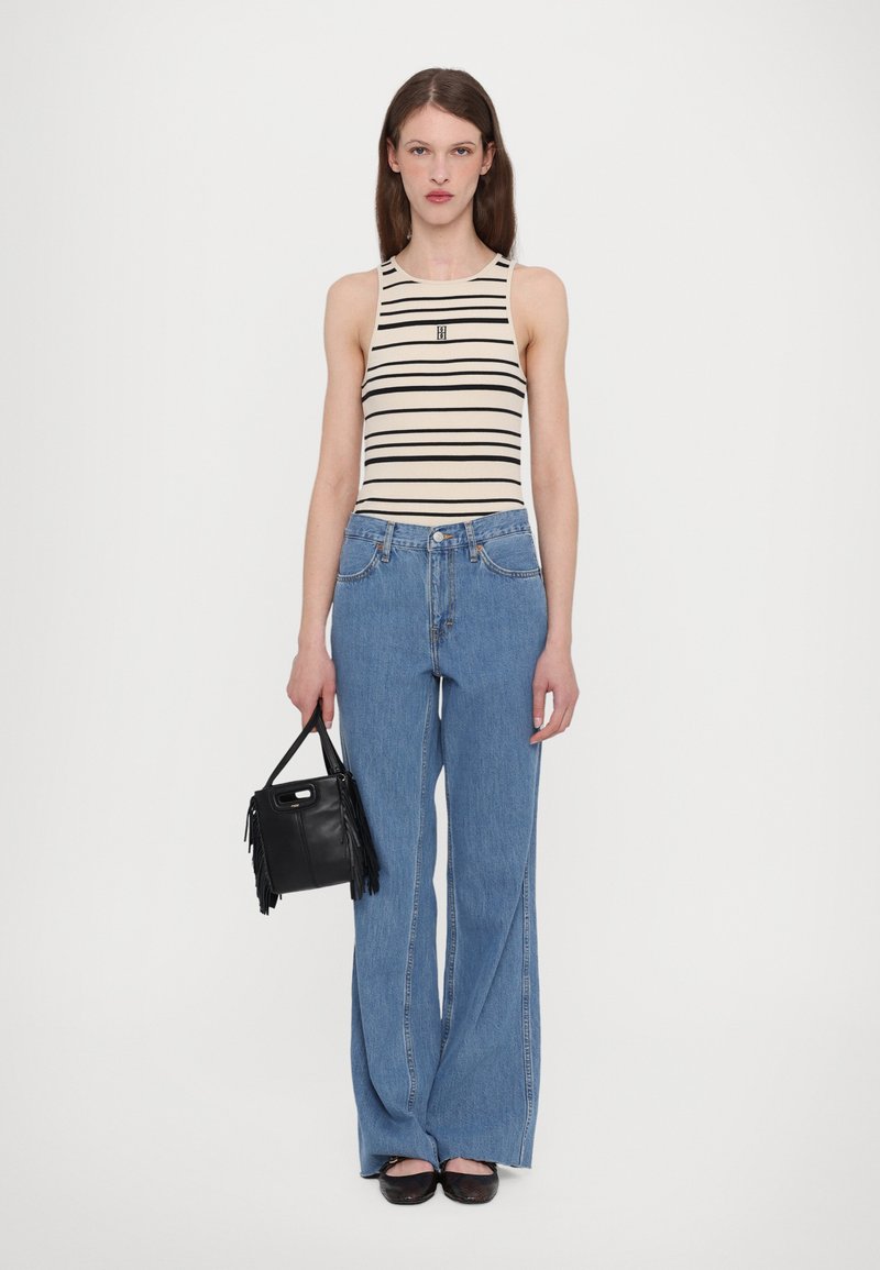 Gestreifter Tanktop in Beige und Schwarz, hochtaillierte blaue Jeans, schwarze Fransenhandtasche und schwarze Ballerinas. Einfaches, lässiges Outfit mit lockerer Passform.