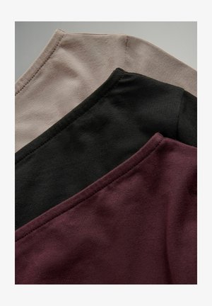 Trīs kokvilnas t-krekli sakrauti: viens gaiši beidzis, viens melns un viens dziļi burgundijas. Katram ir noapaļota kakla izgriezums un gluda tekstūra.