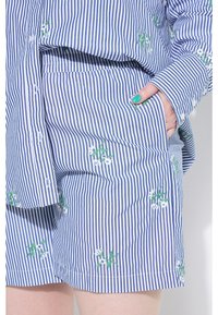 Chemise à manches courtes rayée bleu et blanc avec un short assorti, ornés de broderies florales vertes et blanches, fabriqués en tissu léger.