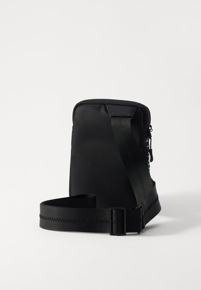 Borsa a tracolla nera realizzata in nylon liscio con forma rettangolare. Dotata di una tracolla regolabile e chiusura con zip sulla parte frontale.