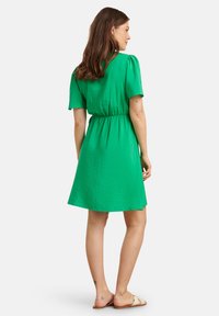 Groene korte jurk met korte mouwen en een ingezette taille. Gemaakt van textuurstof, met een comfortabele pasvorm en een uitlopende zoom.