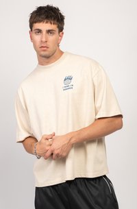 Beige oversized t-shirt made of cotton, featuring a blue graphic with flames and text "I THINK I'M PARANOID" on the chest.