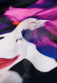 Sciarpa leggera con motivo floreale in rosa, viola e blu su uno sfondo nero, che mette in risalto una trama morbida e trasparente.