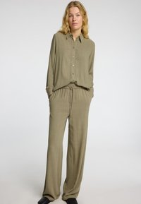 Chemise olive décontractée à boutons avec un col, associée à un pantalon assorti à coupe relaxée, doté d'une taille élastique et de poches latérales.