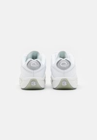 White athletic sneakers with a smooth leather upper, rounded shape, grey accents, and a translucent sole featuring a circular logo.