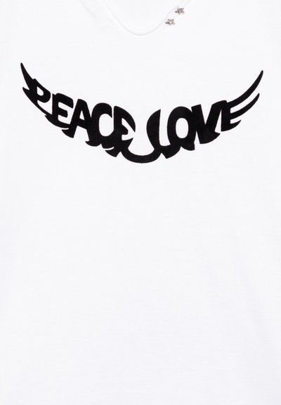 Camiseta blanca con un gran estampado negro del texto "PAZ AMOR" con diseños de alas estilizadas, acentuada por detalles plateados en forma de estrella.