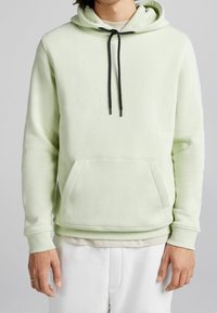 Felpa verde chiaro con tasca a marsupio, coulisse nera, polsini a costine e una superficie liscia. Design a vestibilità rilassata.