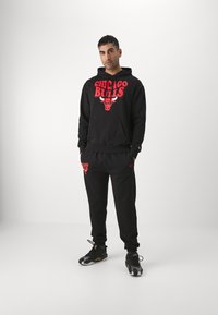 Sudadera con capucha negra con el logo rojo de "Chicago Bulls" y pantalones de chándal a juego. Presenta un bolsillo frontal, puños elásticos y acentos con el logo.