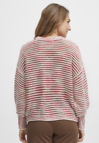 Stickad tröja med breda ärmar, med röd, gräddfärgad och beige randning. Mjuk textur med avslappnad passform och ribbade muddar.