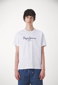 Baltas medvilnės marškinėliai su mėlynai siuvinėtu "Pepe Jeans London" logotipu. Trumpomis rankovėmis ir klasikinio apvalaus kaklo.