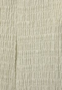 Gros plan sur un tissu beige avec un motif smocké texturé et extensible formant des fronces verticales et horizontales serrées.