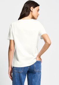 Hvid bomulds t-shirt med korte ærmer, en rund halsudskæring og en afslappet pasform, parret med blå høj talje denimjeans.